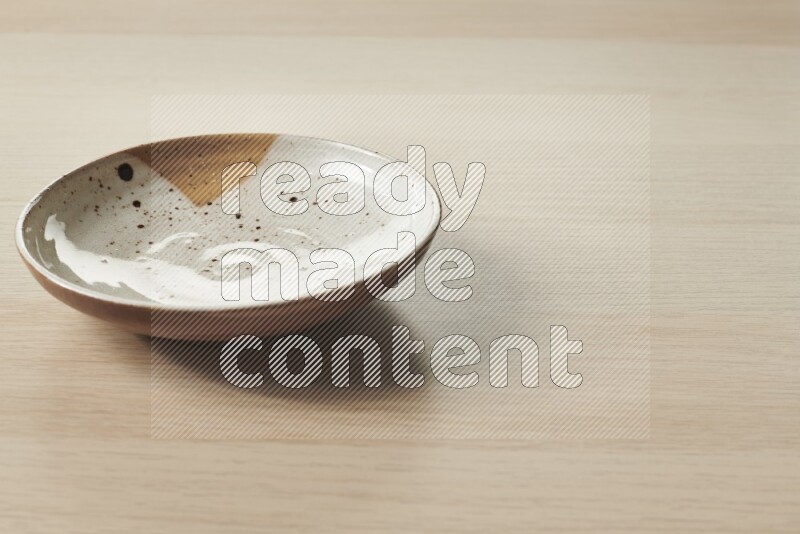 A multicolored pottery plate on light wooden background