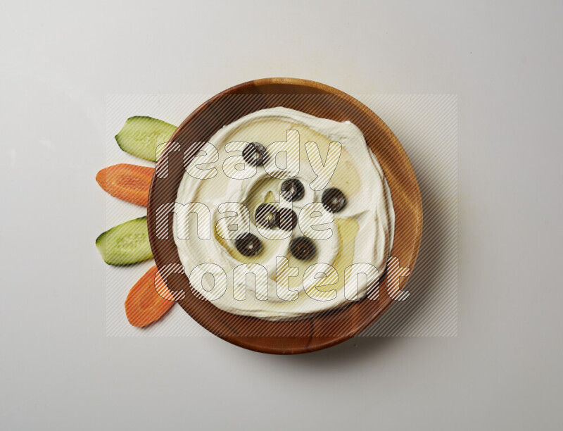 Lebnah garnished with sliced olives in a wooden plate on a white background