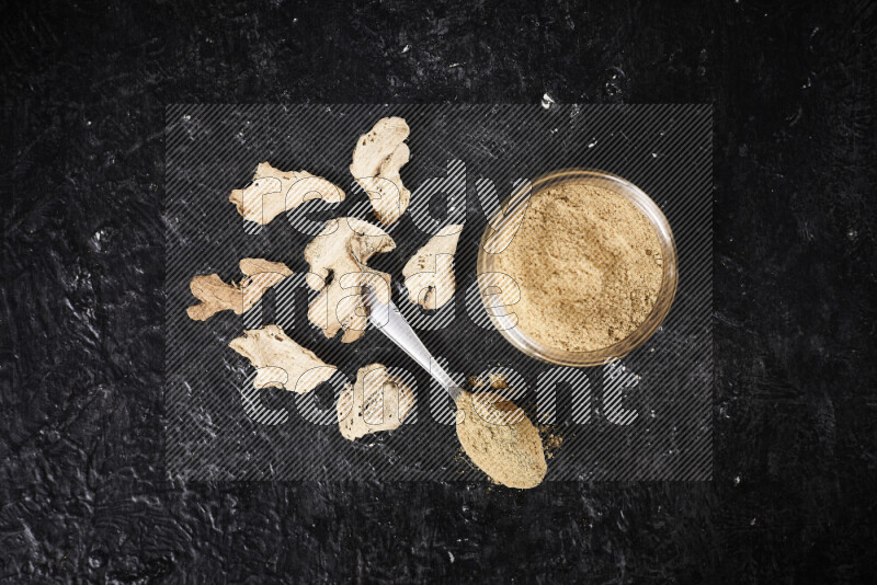 A glass jar full of ground ginger powder on black background