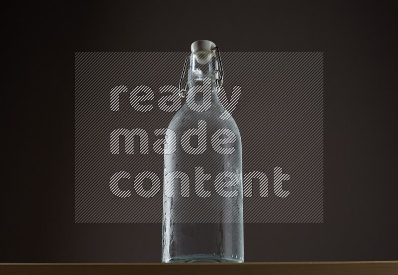 Low angle shot of a bottle of water and ice on grey background