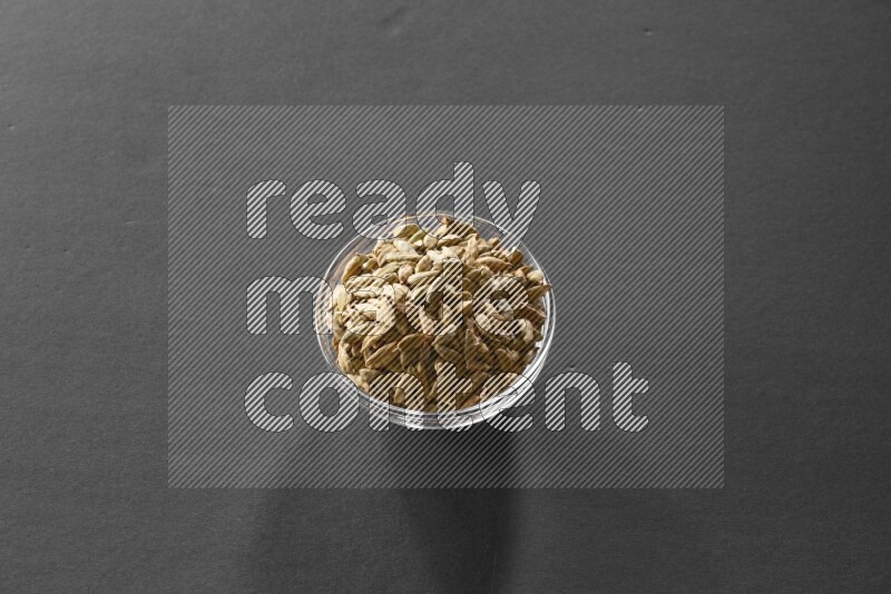 A glass bowl full of cardamom on black flooring