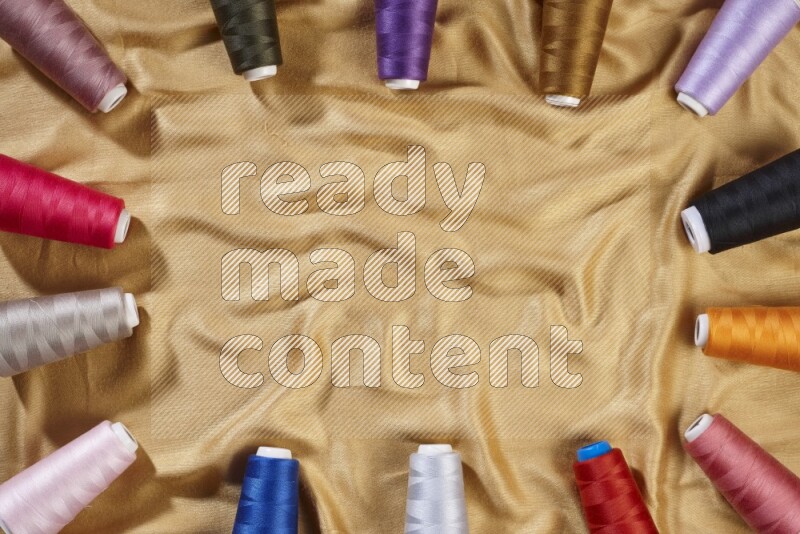 بكرات خيوط الخياطة متعددة الألوان على خلفية من القماش الأصفر