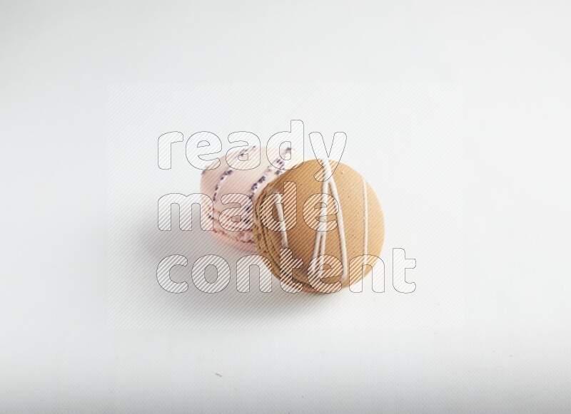 45º Shot of of two assorted Brown Irish Cream, and pink orange blossom macarons on white background