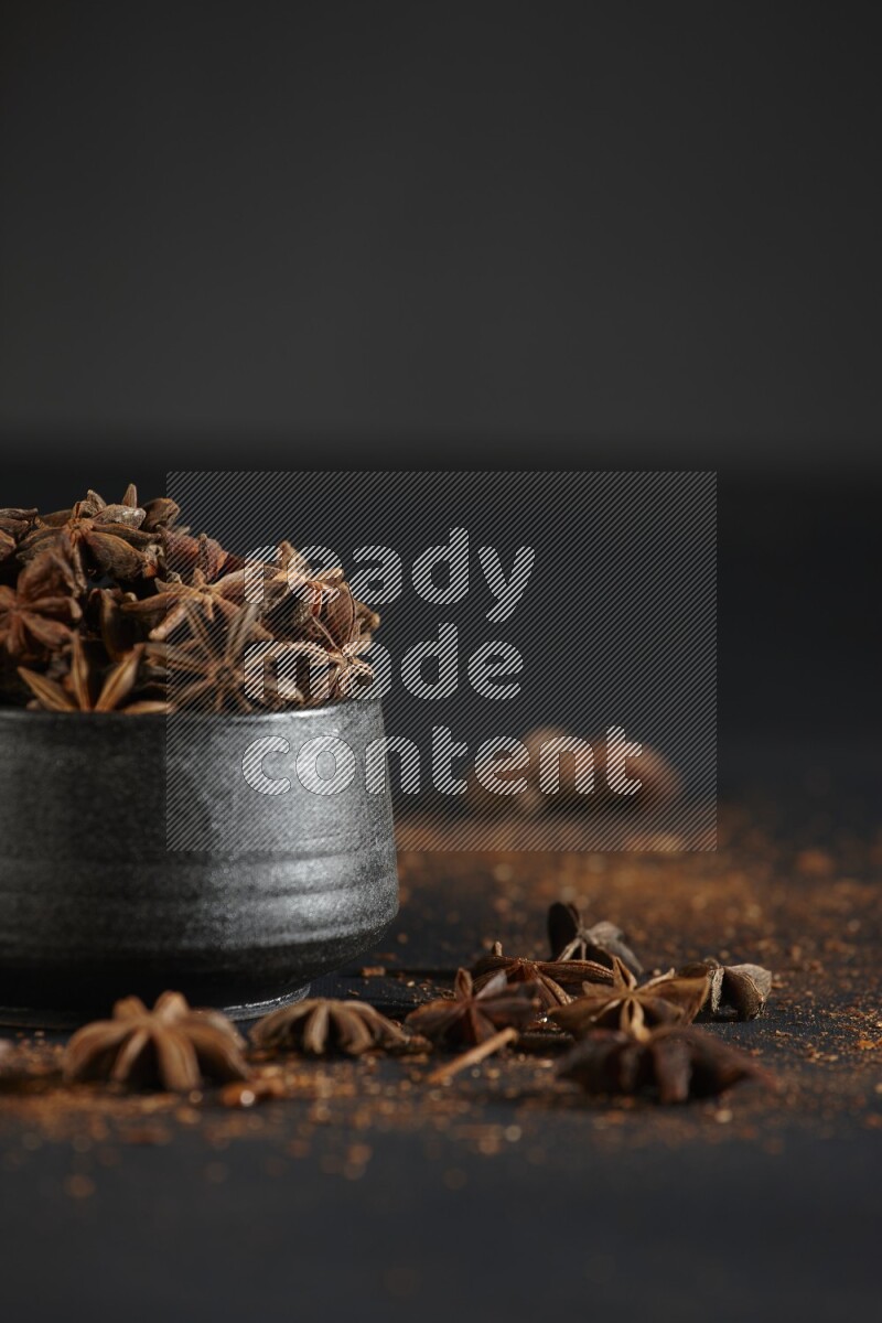 اليانسون النجمي في وعاء أسود مع اليانسون المنثور على خلفية سوداء