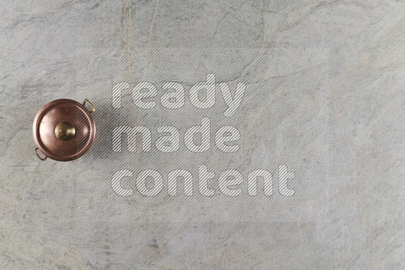 A small copper pot on grey marble background