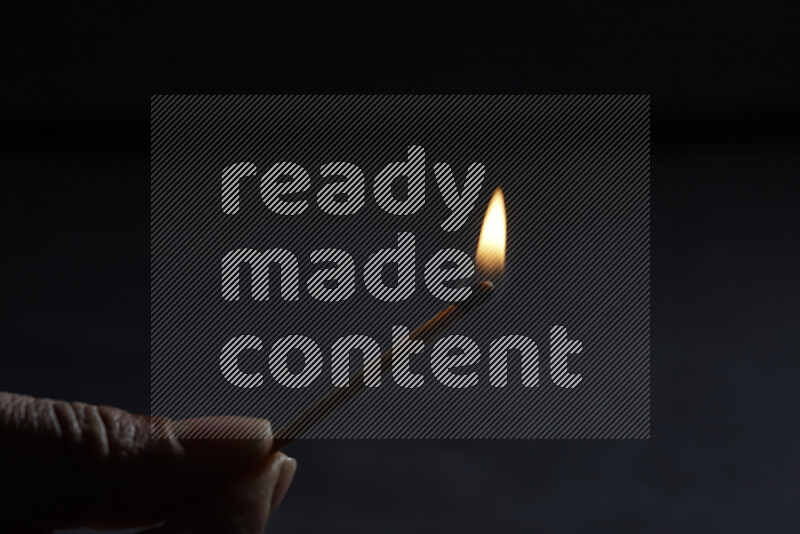 A burning matchstick isolated on dark backdrop