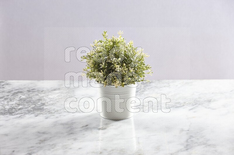 Artificial plant in white pot on grey marble background