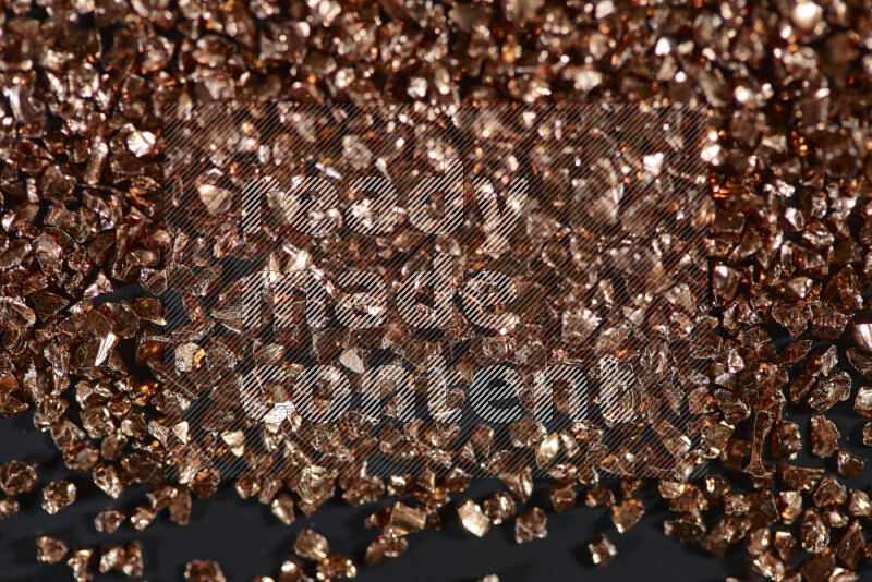 Bronze shimmering fragments of glass scattered on a black background