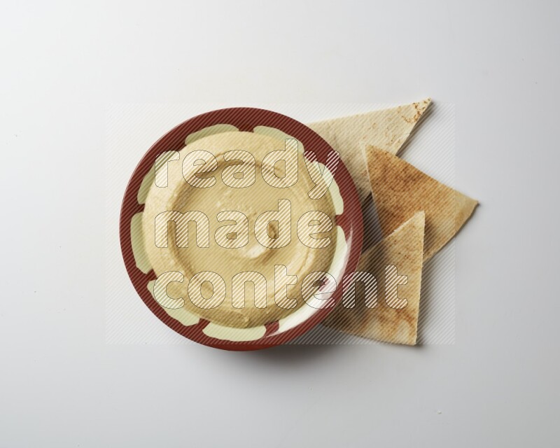 Plain hummus in a traditional plate on a white background
