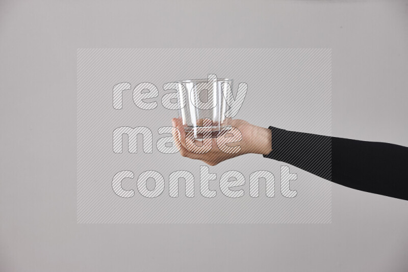 A woman in black abaya holding different glassware in different positions