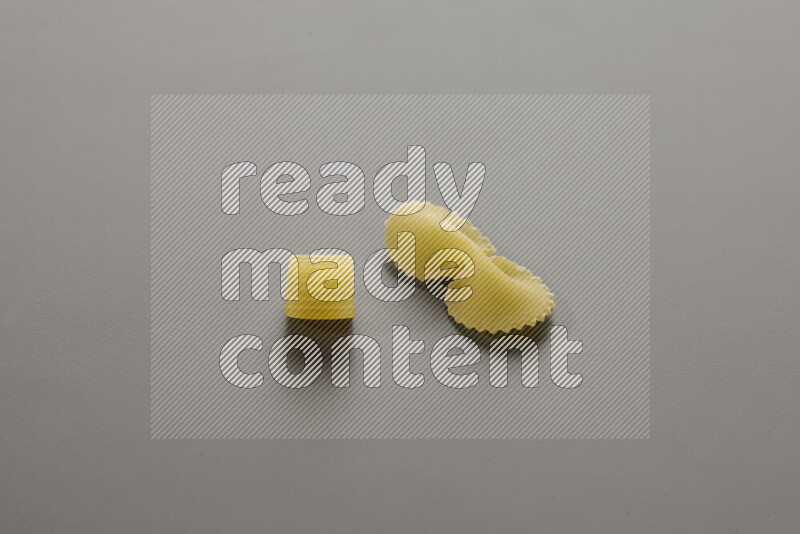 Big rings pasta with other types of pasta on grey background