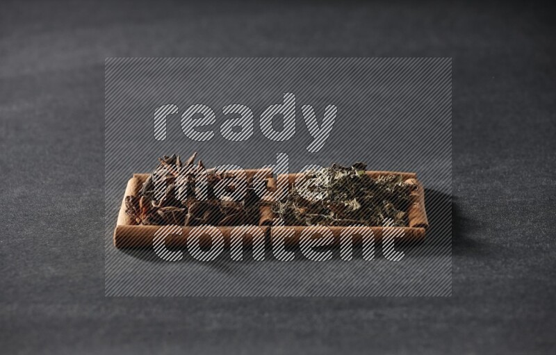 2 squares of cinnamon sticks full of star anise and dried basil on black flooring
