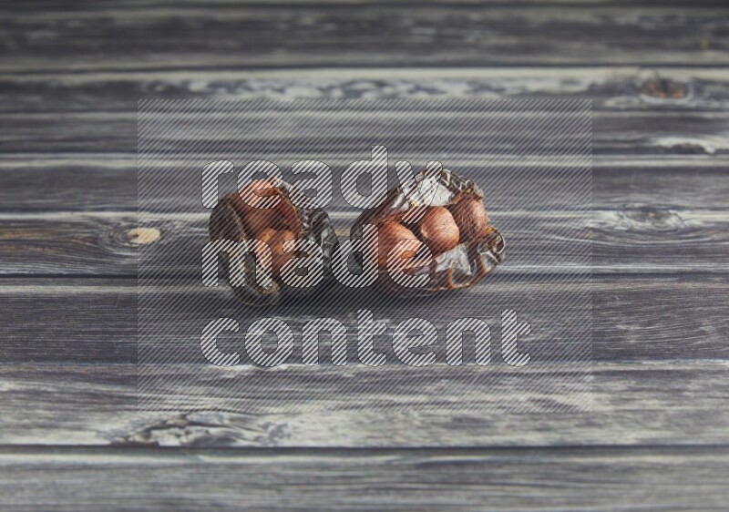 two hazelnut stuffed madjoul dates on a wooden grey background