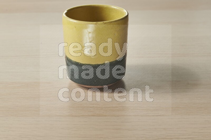 A multicolored pottery cup on light wooden background
