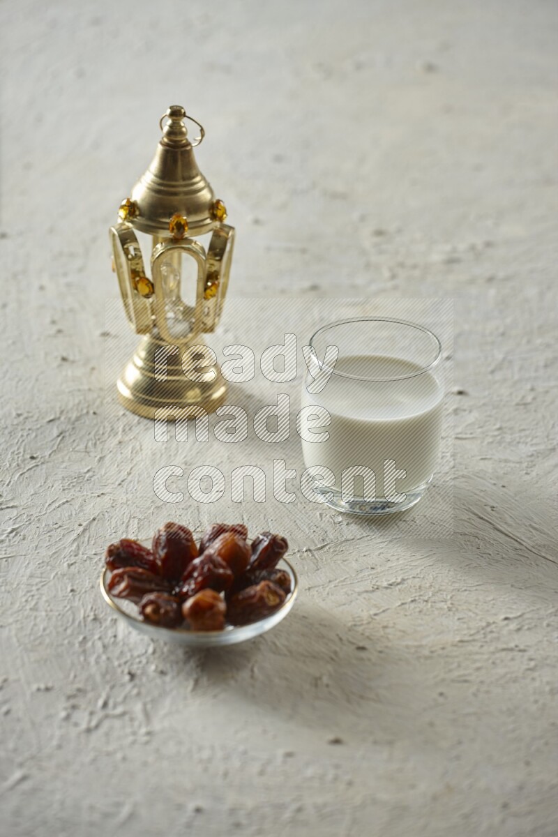 A golden lantern with different drinks, dates, nuts, prayer beads and quran on textured white background