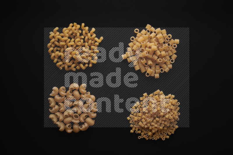 Different pasta types in bunches on black background