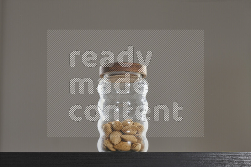 Almonds in a glass jar on black background