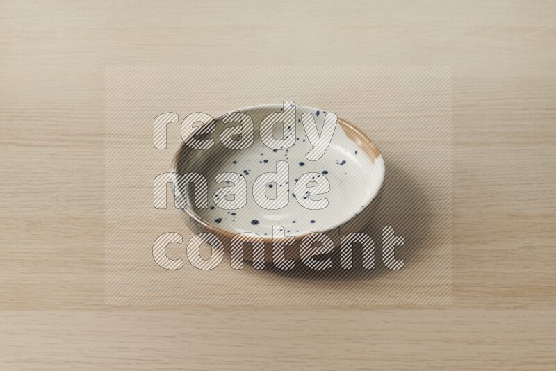 A multicolored pottery bowl on light wooden background