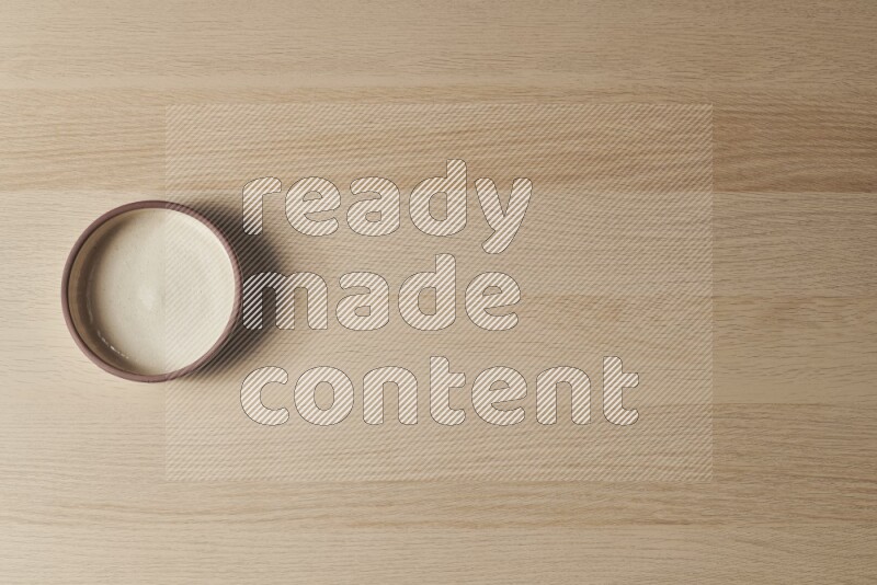 A beige pottery oven bowl on light wooden background