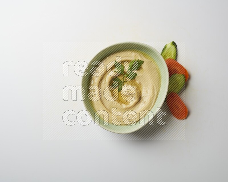 Hummus in a green plate garnished with parsley on a white background