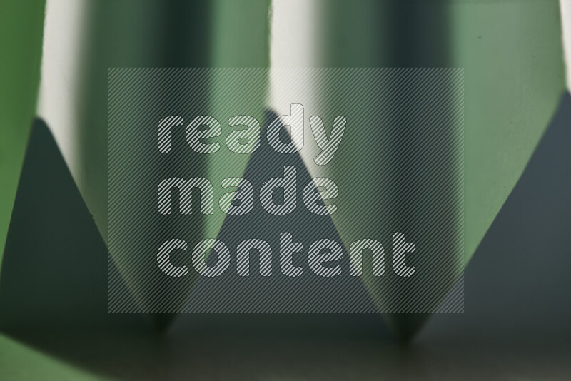 A close-up abstract image showing sharp geometric paper folds in green gradients