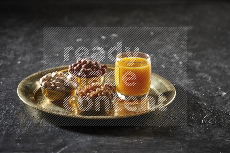 Nuts in metal bowls with qamar eldin on a tray in dark setup