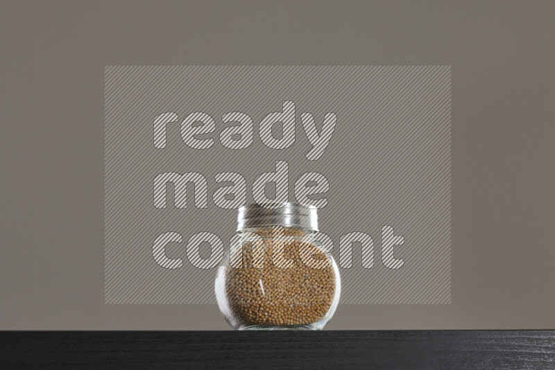 Mustard seeds in a glass jar on black background