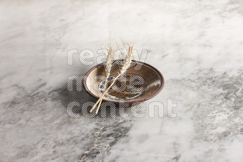 Wheat stalks on decorative pottery plate on grey marble background
