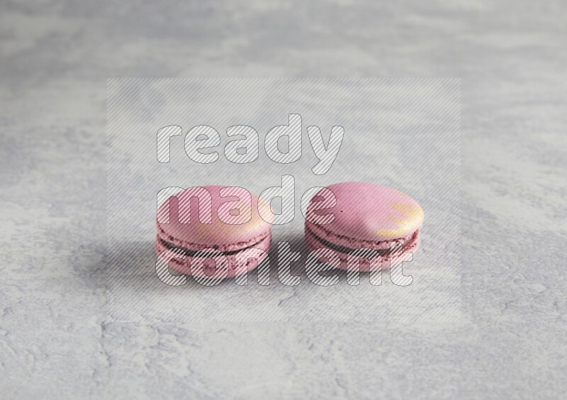 45º Shot of two Purple Strawberry macarons on white  marble background