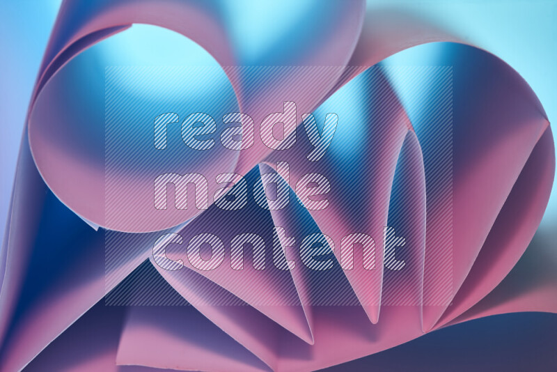 An artistic display of paper folds creating a harmonious blend of geometric shapes, highlighted by soft lighting in blue and pink tones