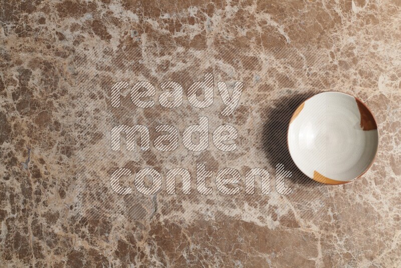 A multicolored pottery bowl on beige marble background