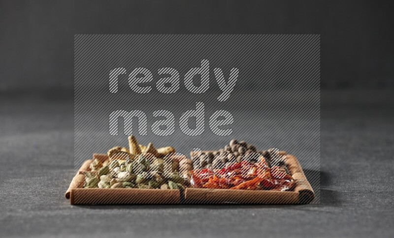 4 squares of cinnamon sticks full of cardamom, dried red chilis, allspice and turmeric fingers on black flooring