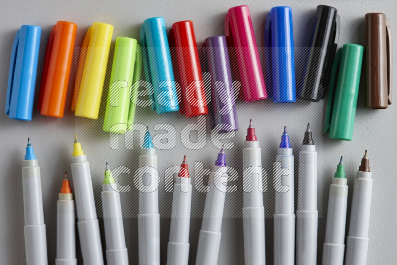 An arrangement of coloring pens in different colors on grey background