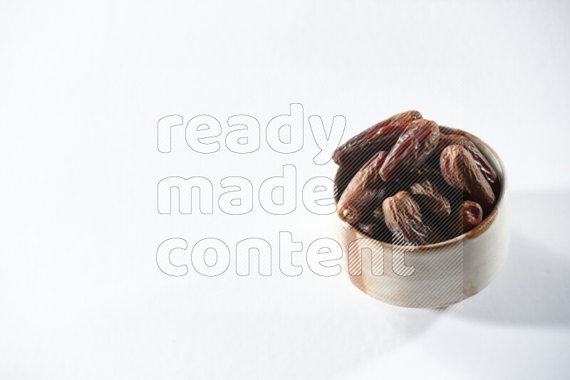 A beige ceramic bowl full of dried dates on a white background in different angles