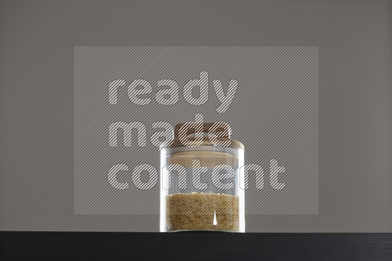 Basmati golden rice in a glass jar on black background