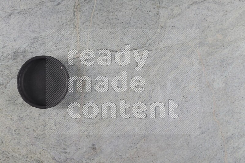 A black pottery bowl on grey marble background