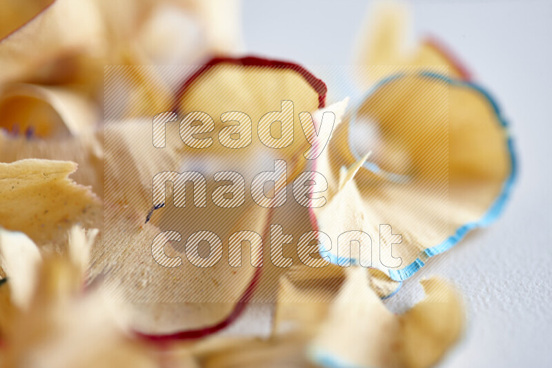 A close-up showing a small pile of pencil shavings with varied color edges on grey background