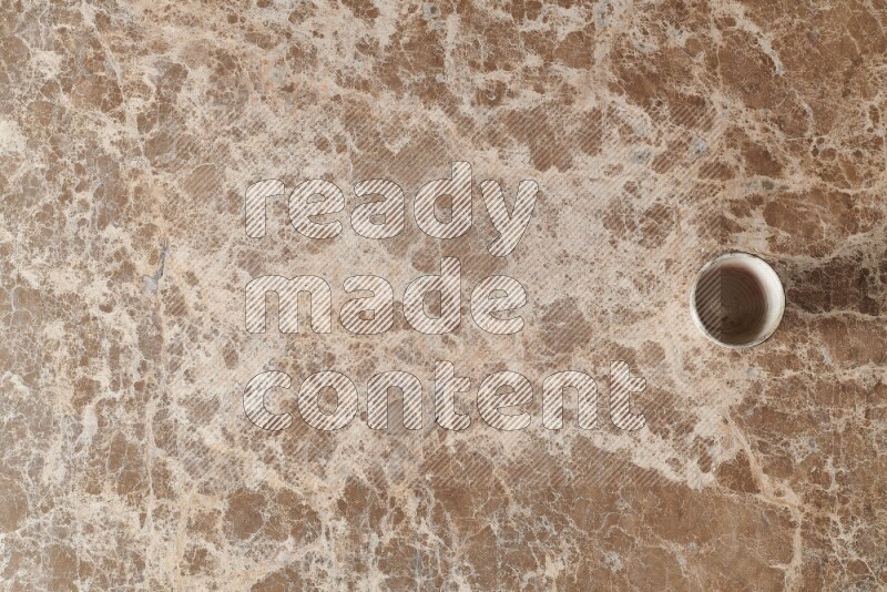 A pottery cup on beige marble background