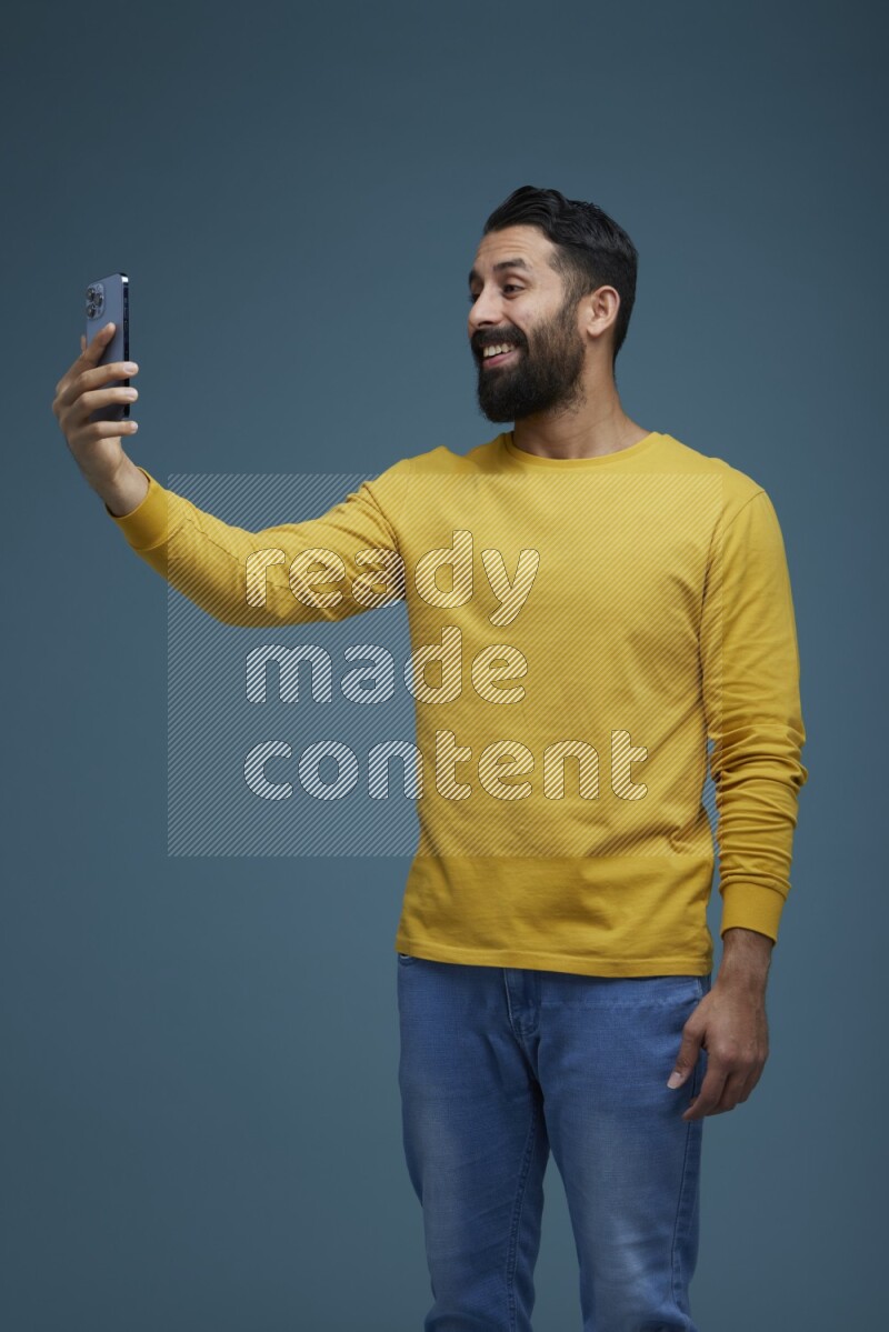 Man Taking a Selfie  in a blue background wearing a yellow shirt