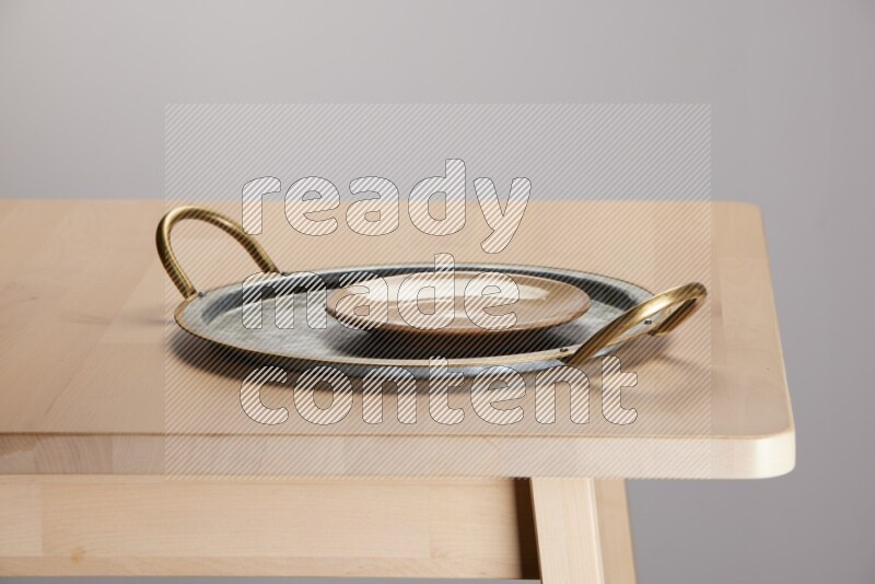 multicolored plate placed on a rounded stainless steel tray with golden handels on the edge of wooden table