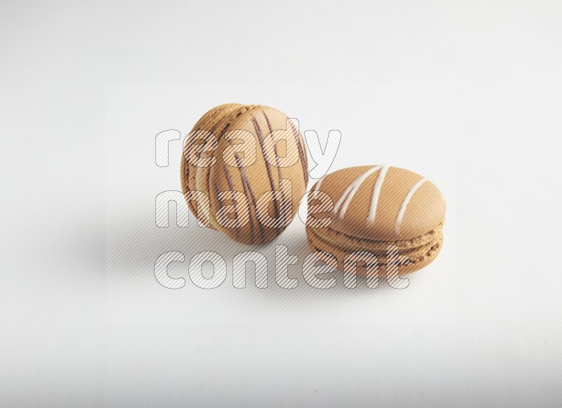 45º Shot of of two assorted Brown Irish Cream, and light brown  Almond Cream macarons on white background