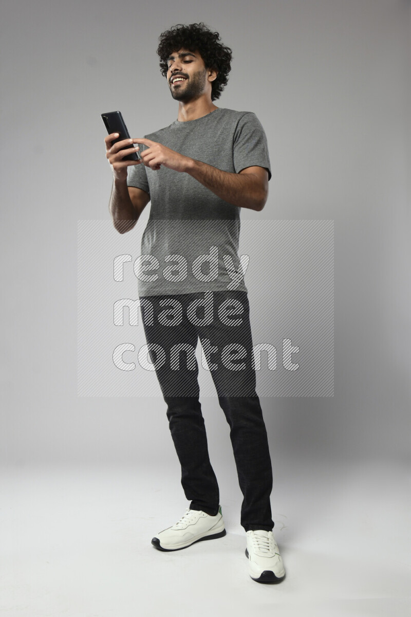 A man wearing casual standing and browsing on the phone on white background