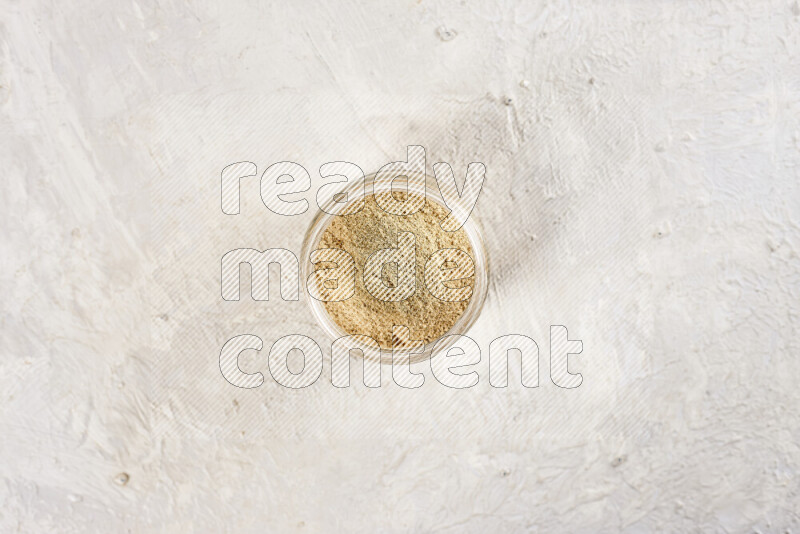 A glass jar full of ground ginger powder on white background