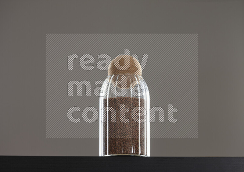 Brown lentils in a glass jar on black background