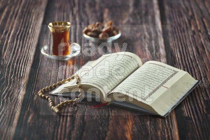 Quran with dates, prayer beads and different drinks all placed on wooden background