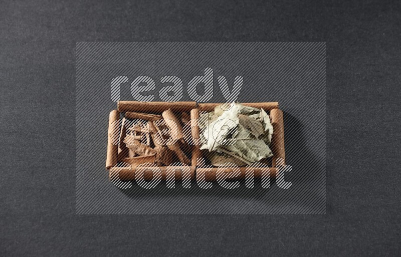 2 squares of cinnamon sticks full of cinnamon and bay laurel leaves on black flooring