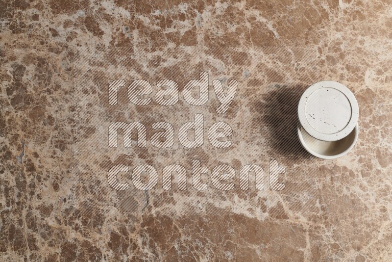 A pottery cup on beige marble background