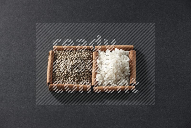 2 squares of cinnamon sticks full of white pepper and salt on black flooring