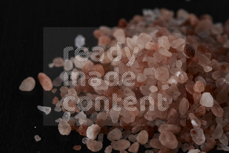 A bunch of coarse himalayan salt crystals on black background