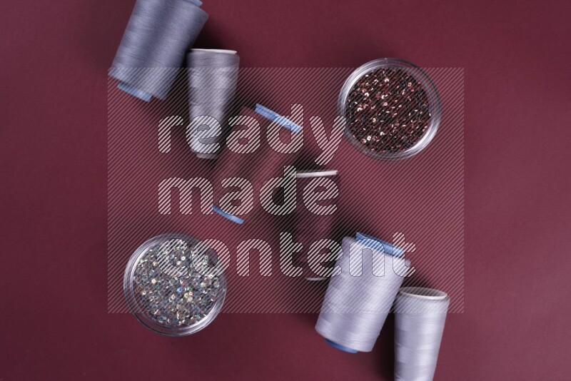 A grey collection of sewing and tailoring tools arranged on a red background